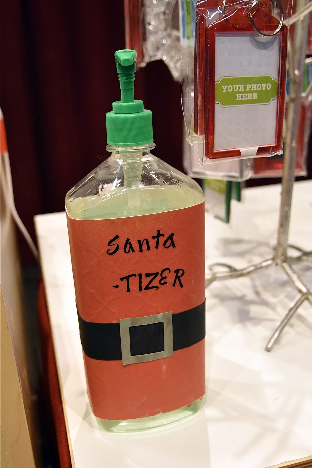 A new spin name on sanitizer sits on a counter, Monday, Nov. 15, 2021, at The Santa Experience the Mall of America in Bloomington, Minn. Where allowed, some malls and big-box stores are offering Santa's guests a choice of full contact or social distance. (AP Photo/Jim Mone)