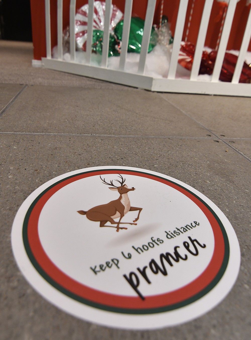 Social distancing signs featuring the names of Santa's reindeer are placed on the floor, Monday, Nov. 15, 2021, at The Santa Experience in the Mall of America in Bloomington, Minn. Where allowed, some malls and big-box stores are offering Santa's guests a choice of full contact or social distance. (AP Photo/Jim Mone)