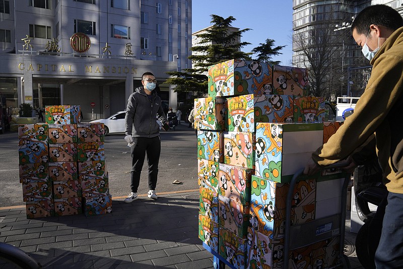 Workers wearing masks delivers boxes of fruits in Beijing, China, Tuesday, Nov. 23, 2021. (AP Photo/Ng Han Guan)