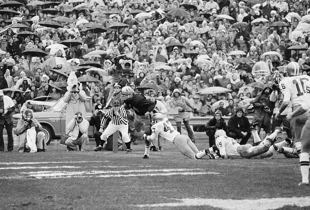 FILE - Army back Bob Hines (44) goes over for one of Army's touchdowns as Navy's Charlie Robinson (47) tries to stop him in the first quarter of a rain-soaked game before nearly 100, 000 spectators, Saturday, Nov. 27, 1971, at Philadelphia's John F. Kennedy. The rivalry game is in many ways the purest form of college football. A game with built-in stakes regardless of circumstances. (AP Photo/File)