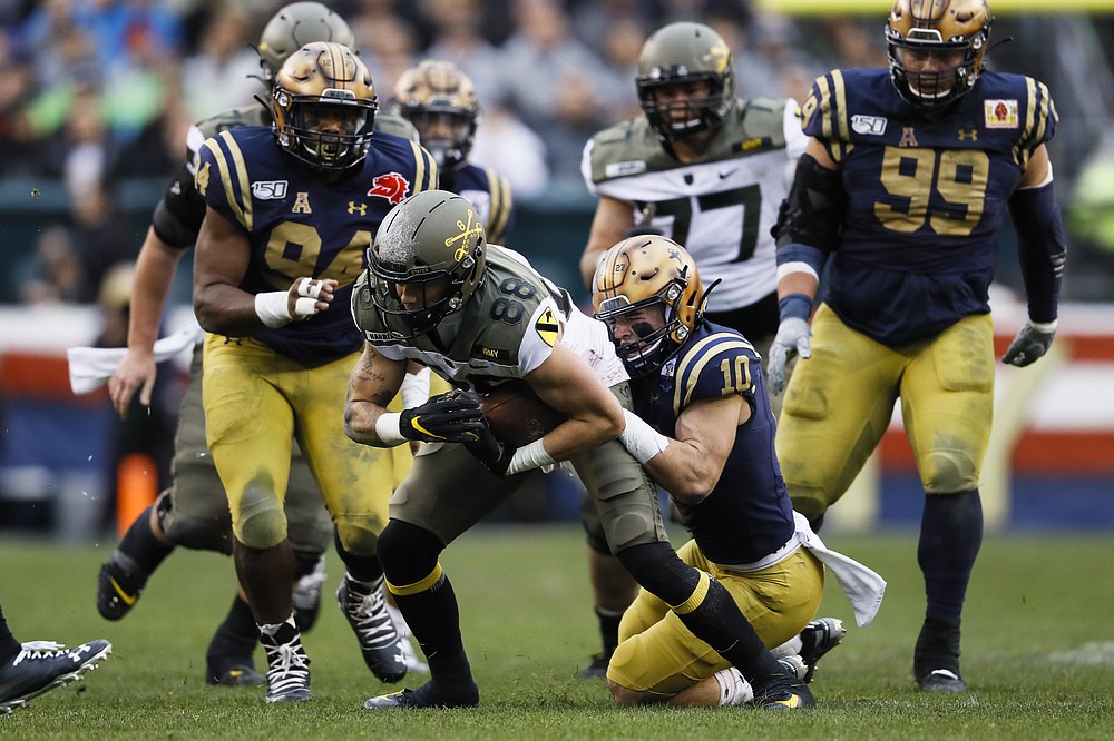 FILE - Army wide receiver Camden Harrison (88) is pulled down by Navy safety Kevin Brennan (10) Perry during the first half of an NCAA college football game, Saturday, Dec. 14, 2019, in Philadelphia. The rivalry game is in many ways the purest form of college football. A game with built-in stakes regardless of circumstances. (AP Photo/Matt Slocum, File)