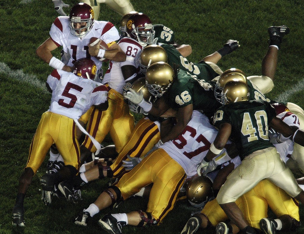 FILE - Southern California's Reggie Bush (5) pushes quarterback Matt Leinhart (11) into the end zone for a final victory over Notre Dame, Oct. 15 2005, in South Bend, Ind. The Bush Push. Defending national champion USC had won 27 straight games, but the Fighting Irish had the Trojans in trouble in South Bend. Leinart sneaked in from the 1-yard line with a big — and against the rules at the time — assist from star tailback Bush's shove for the winning TD. (AP Photo/Joe Raymond, File)