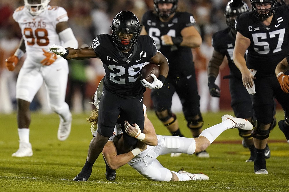 Iowa State running back Breece Hall (28) tries to break a tackle by Texas defensive back Brenden Schooler during the first half of an NCAA college football game, Saturday, Nov. 6, 2021, in Ames, Iowa. (AP Photo/Charlie Neibergall)