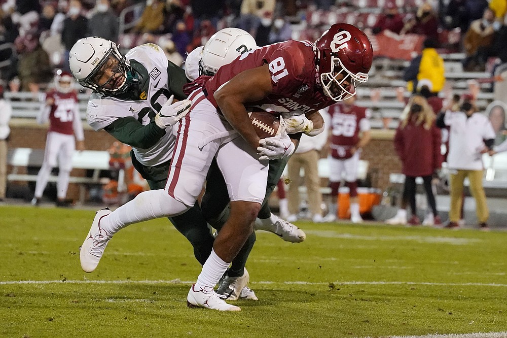 FILE - Oklahoma tight end Brayden Willis (81) fights off Baylor defenders Abram Smith, left, and JT Woods for a touchdown during the second half of an NCAA college football game Saturday, Dec. 5, 2020, in Norman, Okla. Abram Smith was tackling Big 12 running backs at the end of last season as a starting linebacker for Baylor. He is now bruising defenders as the league's leading rusher. (AP Photo/Sue Ogrocki, File)