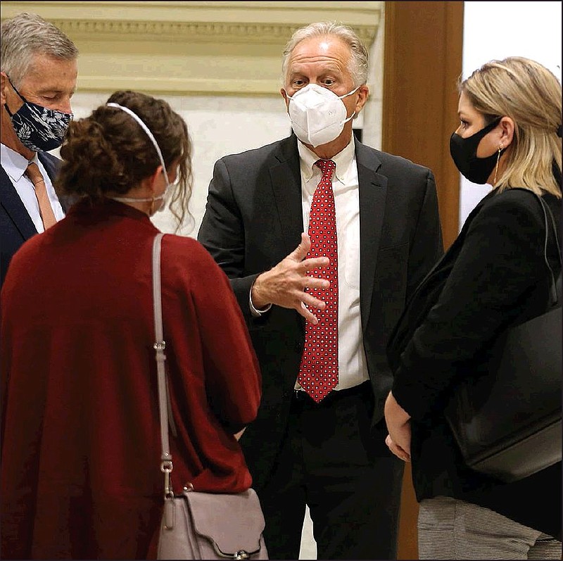 Marion School District Superintendent Glen Fenter (center) and attorney Chris Heller (left) talk with plaintiffs Veronica McClane (center left) and Ashley Simmons on Monday during a recess in the hearing at the Pulaski County Courthouse in Little Rock. (Arkansas Democrat-Gazette/Thomas Metthe)