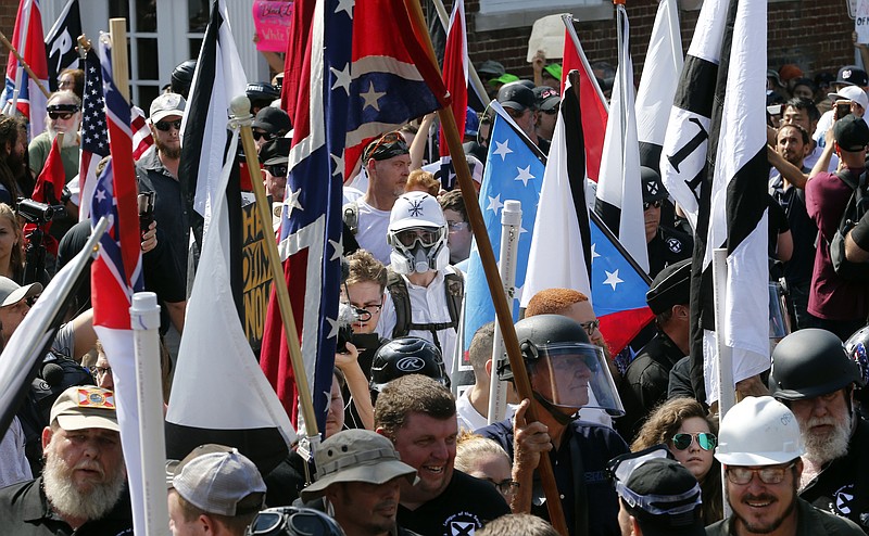 FILE - White nationalist demonstrators walk into the entrance of Lee Park surrounded by counter demonstrators in Charlottesville, Va., Saturday, Aug. 12, 2017.   A jury began deliberations Friday, Nov. 19, 2021, in a civil trial of white nationalists accused of conspiring to commit racially motivated violence at the deadly &#x201c;Unite the Right&#x201d; rally in Charlottesville in 2017.(AP Photo/Steve Helber)