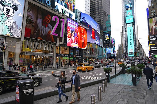 Pedestrians walk through Times Square while taking pictures , Monday, Nov. 15, 2021, in New York. Even as visitors again crowd below the jumbo screens in New York’s Times Square, the souvenir shops, restaurants, hotels and entrepreneurs within the iconic U.S. landmark are still reeling from a staggering pandemic. (AP Photo/Seth Wenig)