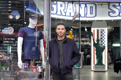 David Cohen, an owner of Grand Slam, a souvenir and sports apparel store, poses for a picture at the store in Times Square, Monday, Nov. 15, 2021, in New York. Even as visitors again crowd below the jumbo screens in New York’s Times Square, the souvenir shops, restaurants, hotels and entrepreneurs within the iconic U.S. landmark are still reeling from a staggering pandemic. (AP Photo/Seth Wenig)