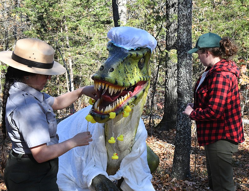 Hot Springs National Park Ranger/Anniversary Coordinator Ashley Waymouth, left and Hot Springs National Park archaeologist Victoria Reichard decorate a dinosaur for Dino-Lites at Mid-America Science Museum. Dino-Lites opens on Friday. - Photo by Tanner Newton of The Sentinel-Record
