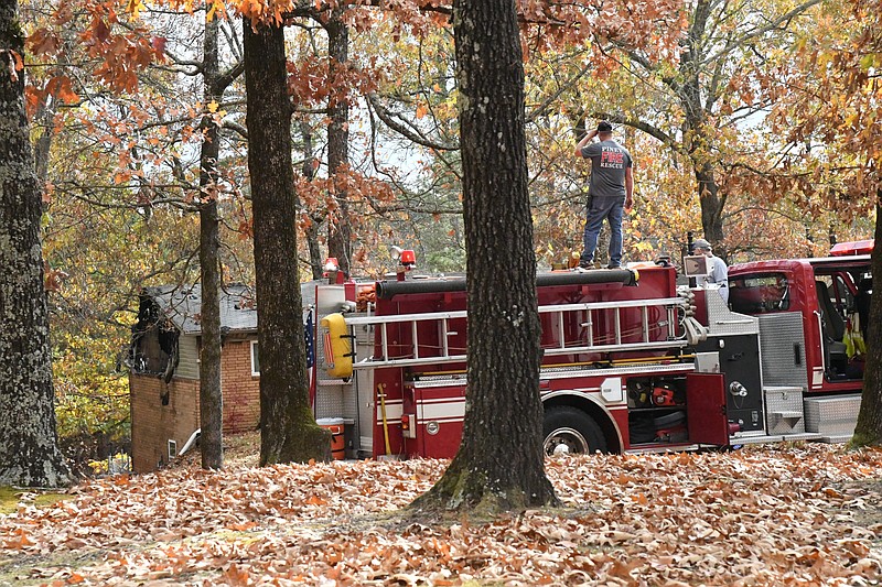 Piney Fire Chief Scott Miser stands atop a 70 West fire truck, watching 70 West firefighters put out a fire at 229 Joy Drive on Wednesday. - Photo by Tanner Newton of The Sentinel-Record