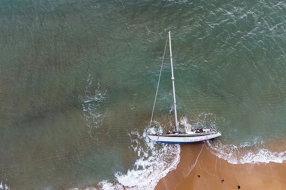 A sailboat used by smugglers to transport migrants and refugees is beached on Le Cannelle beach in Isola Capo Rizzuto, Calabria region, Southern Italy, Saturday, Nov. 13, 2021. Thousands of refugees have arrived in Italy this fall by a lesser-known migrant route, the Calabrian route from Turkey, paying heftier smuggling fees to travel on recreational sailboats that can be less conspicuous than the crammed inflatable boats used in the Central Mediterranean. (AP Photo/Alessandra Tarantino)