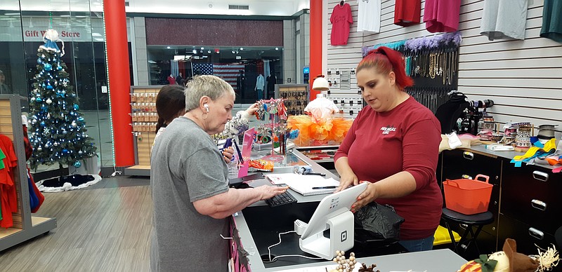 BG's Sassy Creations sells mostly handmade items, from bows to clothes to even weapons and tumblers. Here, Laurie Douglass helps out a customer with some holiday needs. (Staff photo by Junius Stone)