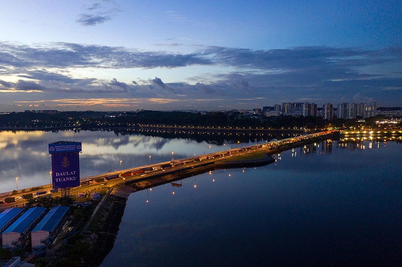 Commercial and residential buildings stand in Singapore, right, as vehicles travel along the causeway across the Straits of Johor at dawn above Johor Bahru, Johor, Malaysia, on June 20, 2019. MUST CREDIT: Bloomberg photo by SeongJoon Cho.