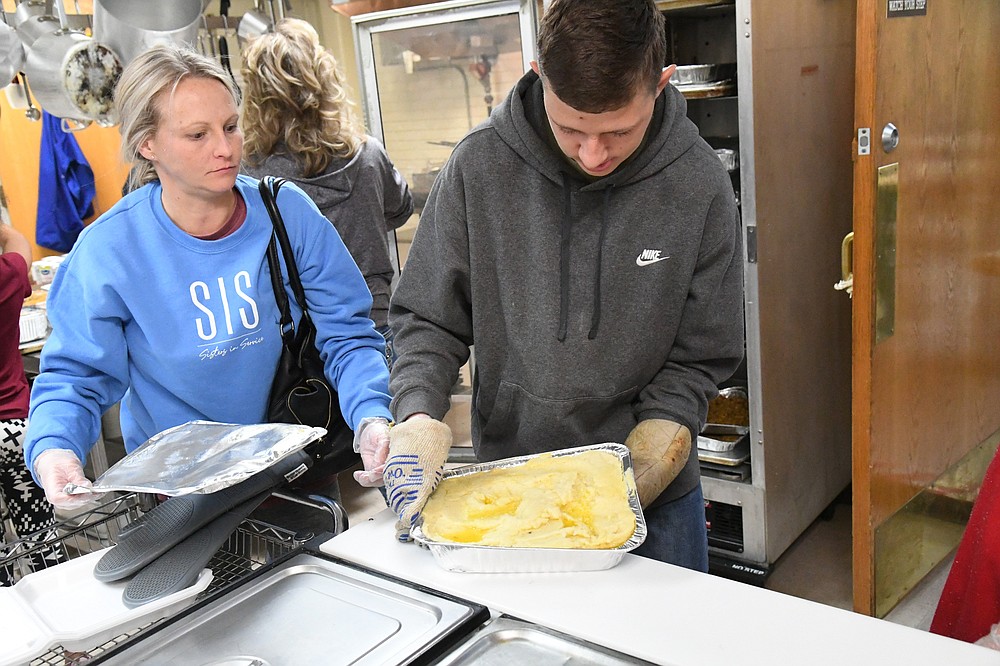 Volunteers Ashley Allison, left, and Keith Hardage prepare mashed potatoes during The Salvation Army’s Thanksgiving meal on Wednesday night. - Photo by Tanner Newton of The Sentinel-Record