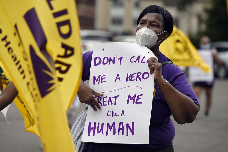 FILE - Clarissa Johnson of Hartford marches with long-term care members of the New England Health Care Employees Union, during a rally to demand new laws to protect long-term caregivers and consumers, July 23, 2020, at the State Capitol in Hartford, Conn. Connecticut essential state employees, who worked long hours during the COVID-19 pandemic, are still waiting for &quot;hero pay&quot; from $22.5 million in federal pandemic funds set aside in the state budget. (AP Photo/Jessica Hill, File)