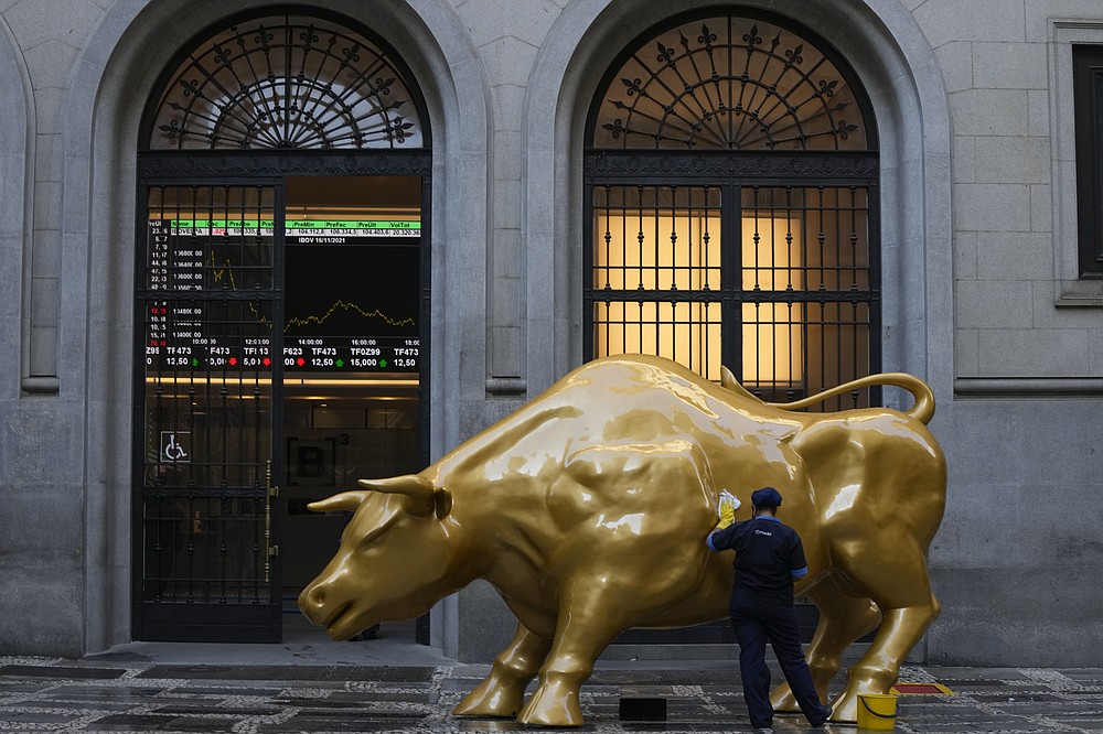 A worker cleans off a protest sign that read &amp;quot;hungry&amp;quot; in Portuguese, placed by activists on the Golden Bull, a replica of Wall street Charging Bull symbolizing the financial market outside the Brazilian B3 Stock Exchange in Sao Paulo, Brazil, Wednesday, Nov. 17, 2021. (AP Photo/Andre Penner)