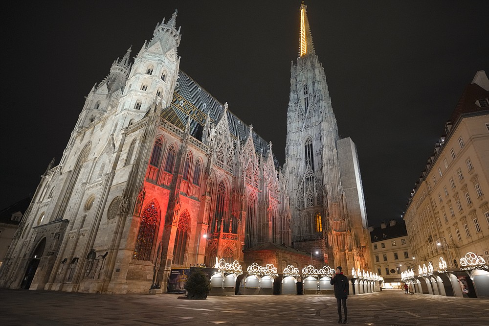 FILE - A man takes photographs in a deserted square at the St. Stephen&#x27;s Cathedral in Vienna, Austria, Nov. 22, 2021. Despite the pandemic inconveniences, stall owners selling ornaments, roasted chestnuts and other holiday-themed items in Frankfurt and other European cities are relieved to be open at all for their first Christmas market in two years, especially with new restrictions taking effect in Germany, Austria and other countries as COVID-19 infections hit record highs. (AP Photo/Vadim Ghirda, File)