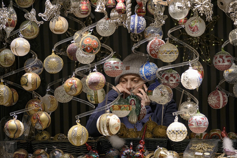 FILE - A vendor speaks on the phone at a Christmas market in Vienna, Austria, Nov. 20, 2021. Despite the pandemic inconveniences, stall owners selling ornaments, roasted chestnuts and other holiday-themed items in Frankfurt and other European cities are relieved to be open at all for their first Christmas market in two years, especially with new restrictions taking effect in Germany, Austria and other countries as COVID-19 infections hit record highs. (AP Photo/Vadim Ghirda, File)