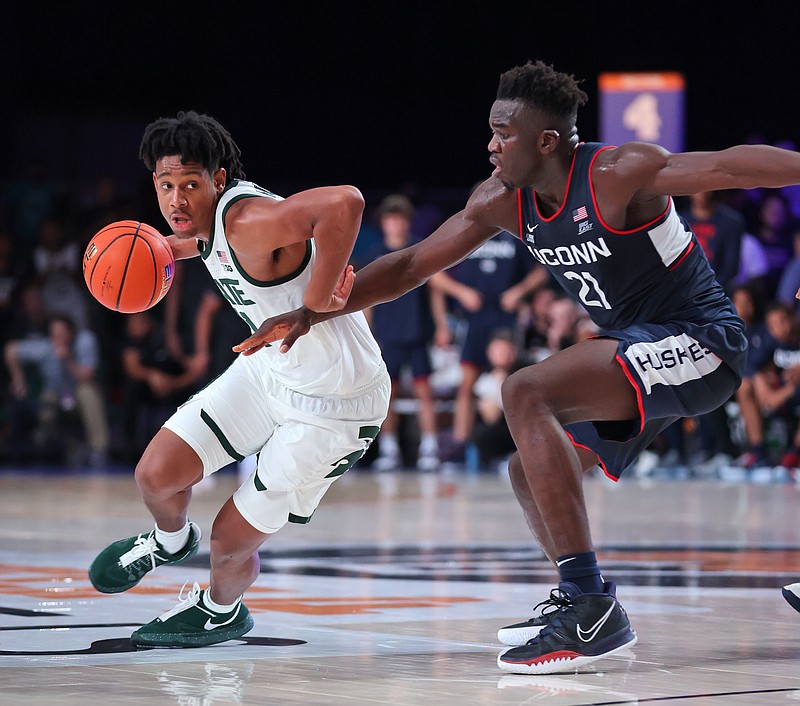 In this photo provided by Bahamas Visual Services,  Michigan State guard A.J. Hoggard (11) drives as Connecticut forward Adama Sanogo (21) defends during an NCAA basketball game at Paradise Island, Bahamas, Thursday. - Photo by Tim Aylen/Bahamas Visual Services via The Associated Press