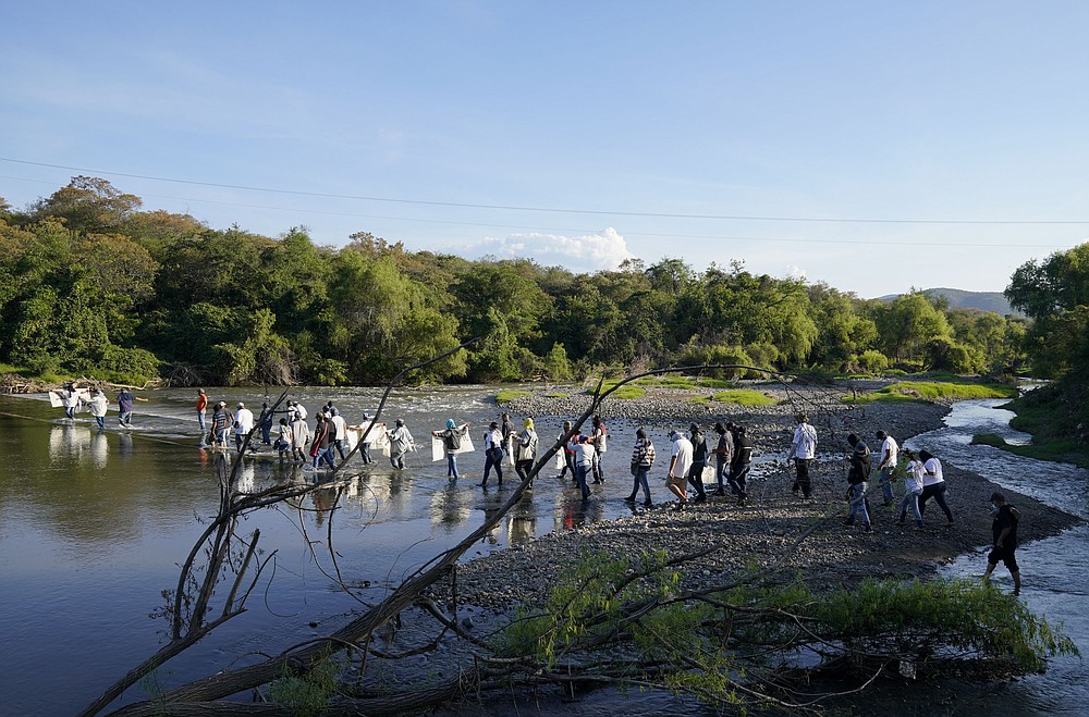 Residents from Aguililla and other nearby communities wade across a river to confront an army squad blocking a dirt road leading out of Jalisco territory, in Loma Blanca, Mexico, Tuesday, Nov. 16, 2021. The residents, who are fed up with the army&amp;#x2019;s strategy of simply separating the Jalisco and the Michoacan-based Viagras gangs, want the army to either fight both cartels, or at least let the two gangs fight it out amongst themselves. (AP Photo/Eduardo Verdugo)