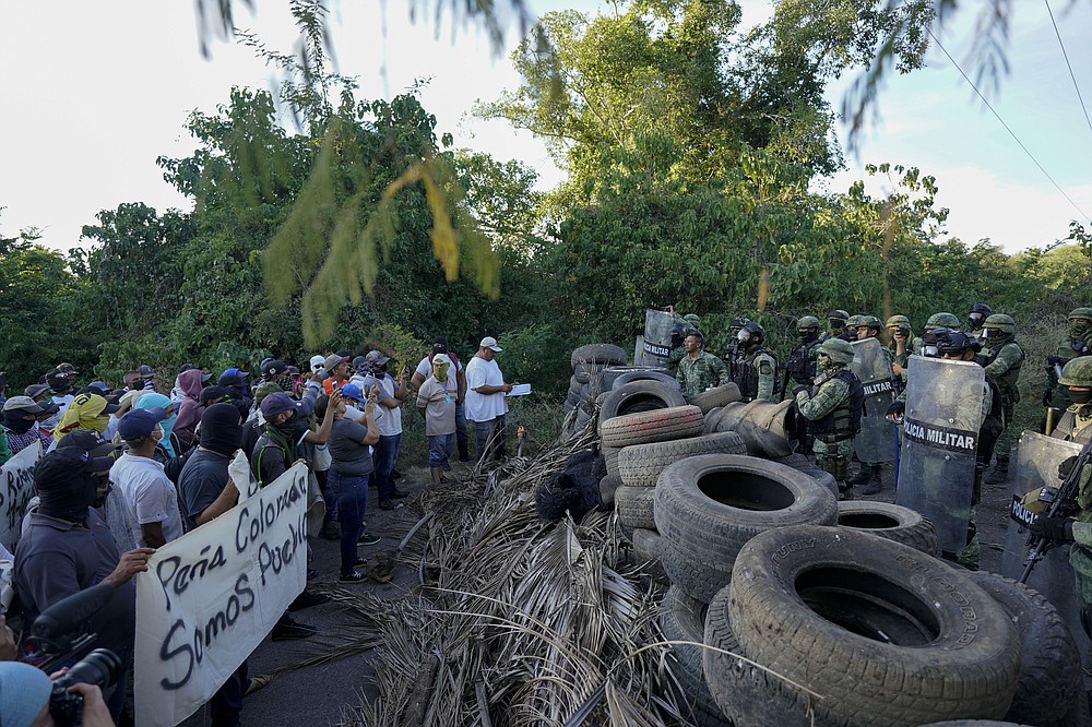 Mexican soldiers take cover behind a barricade of car tires against protesters who are fed up with the army&amp;#x2019;s strategy of simply separating the Jalisco and the Michoacan-based Viagras gangs, during a march against roadblocks in Loma Blanca, Mexico, Tuesday, Nov. 16, 2021.  (AP Photo/Eduardo Verdugo)