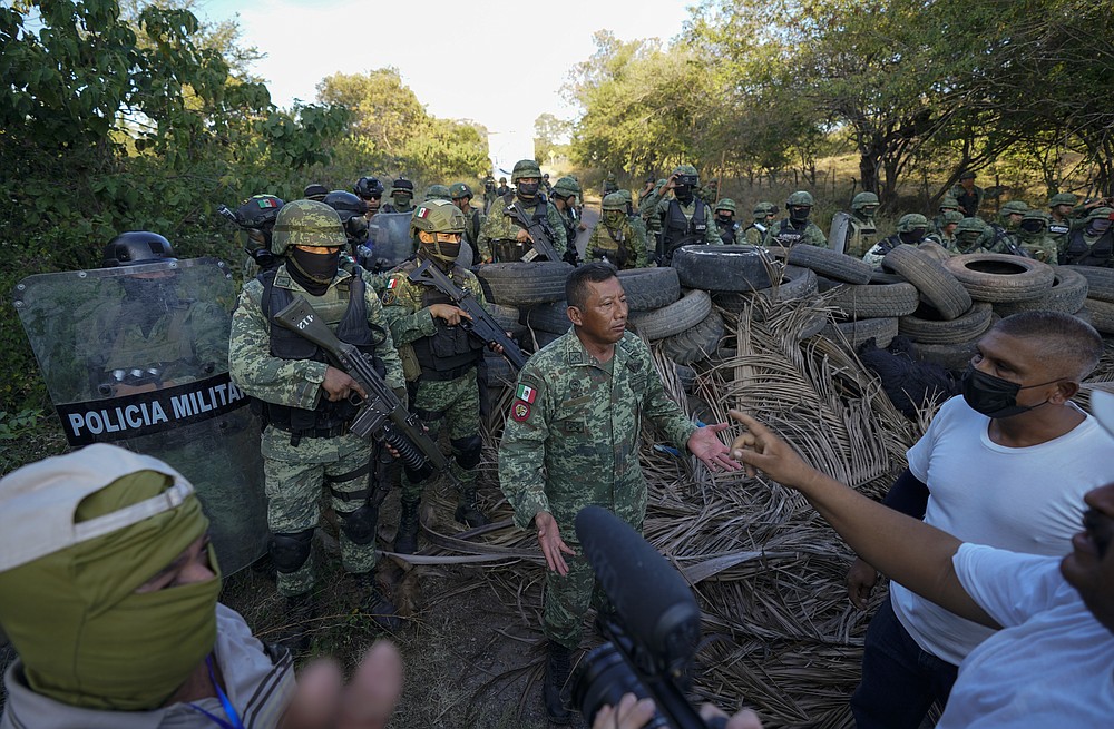 Residents who are fed up with the army&amp;#x2019;s strategy of simply separating the Jalisco and the Michoacan-based Viagras gangs, confront Mexican soldiers taking cover behind a barricade of car tires, in Loma Blanca, Mexico, Tuesday, Nov. 16, 2021. The residents, who are fed up with the army&amp;#x2019;s strategy of simply separating the Jalisco and the Michoacan-based Viagras gangs, want the army to either fight both cartels, or at least let the two gangs fight it out amongst themselves. (AP Photo/Eduardo Verdugo)