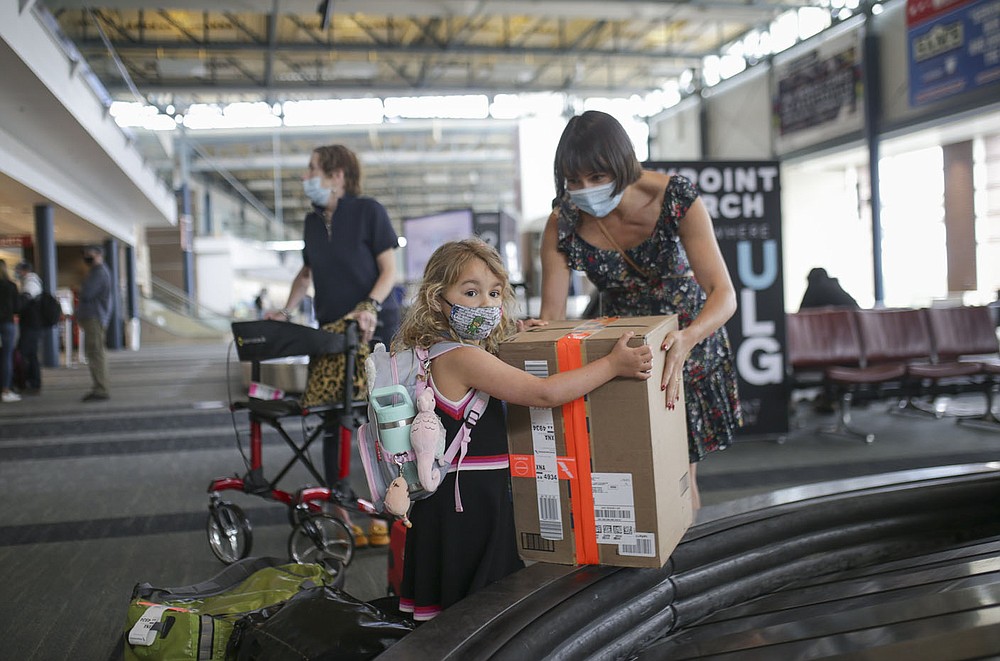 Marielle Mincey, 4, (left) helps her mom Lydia Mincey of Wilmington, N.C., pick up a package from baggage claim in April at Northwest Arkansas National Airport in Highfill. Go to  nwaonline.com/211128Daily/ for today&#x27;s photo gallery. 
(File Photo/NWA Democrat-Gazette/Charlie Kaijo)