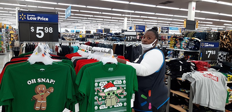 Guikima Walker, apparel associate at WalMart on Arkansas Boulevard, organizes the Christmas wear now going out on the shelves. She said the customer flow was steady and calm throughout Black Friday. (Staff photo by Junius Stone)