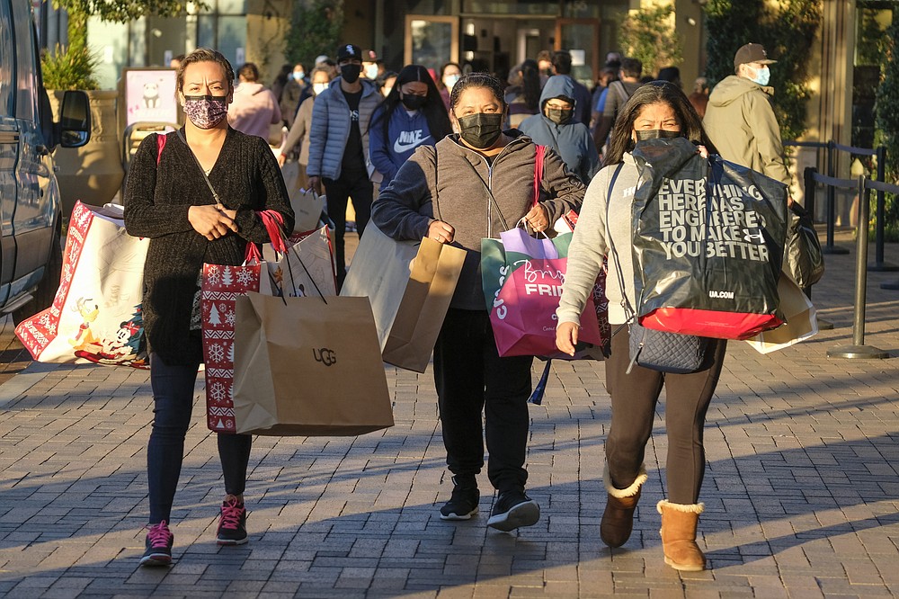 Black Friday shoppers wearing face masks carry bags at the Citadel Outlets in Commerce, Calif., Friday, Nov. 26, 2021. Retailers are expected to usher in the unofficial start to the holiday shopping season today with bigger crowds than last year in a closer step toward normalcy. But the fallout from the pandemic continues to weigh on businesses and shoppers&amp;#x2019; minds.  (AP Photo/Ringo H.W. Chiu)