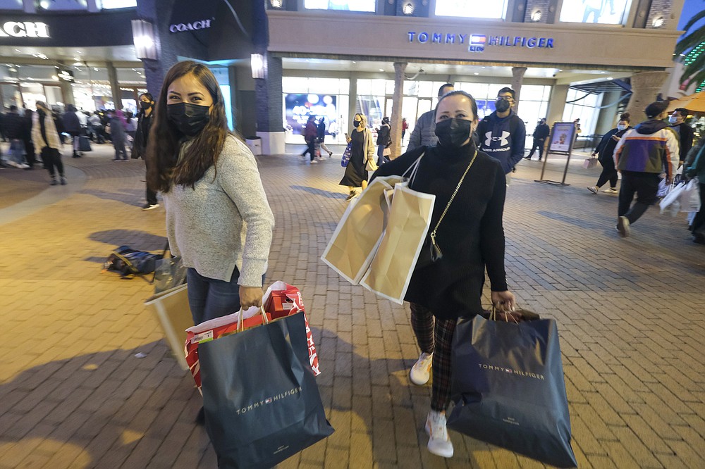 Black Friday shoppers wearing face masks carry bags at the Citadel Outlets in Commerce, Calif., Friday, Nov. 26, 2021.  Retailers are expected to usher in the unofficial start to the holiday shopping season today with bigger crowds than last year in a closer step toward normalcy. But the fallout from the pandemic continues to weigh on businesses and shoppers&amp;#x2019; minds.(AP Photo/Ringo H.W. Chiu)