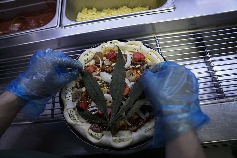 A cannabis leaf is put on a pizza at a restaurant in Bangkok, Thailand on Nov. 24, 2021. The Pizza Company, a Thai major fast food chain, has been promoting its &quot;Crazy Happy Pizza&quot; this month, an under-the-radar product topped with a cannabis leaf. It&#x2019;s legal but won&#x2019;t get you high.  (AP Photo/Sakchai Lalit)