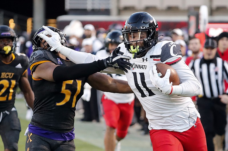 Cincinnati's Leonard Taylor (11) stiff-arms East Carolina's Aaron Ramseur (51) after catching the ball during the first half of an NCAA football game in Raleigh, N.C., Friday. - Photo by Karl B DeBlaker of The Associated Press