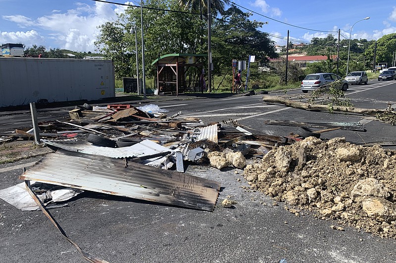 Debris left by demonstrators block a street of Le Gosier, Guadeloupe island, Sunday, Nov.21, 2021. French authorities sent police special forces to the Caribbean island of Guadeloupe, an overseas territory of France, as protests over COVID-19 restrictions erupted into rioting and looting for the third day in a row. On Sunday, many road blockades by protesters made traveling across the island nearly impossible. (AP Photo/Elodie Soupama)
