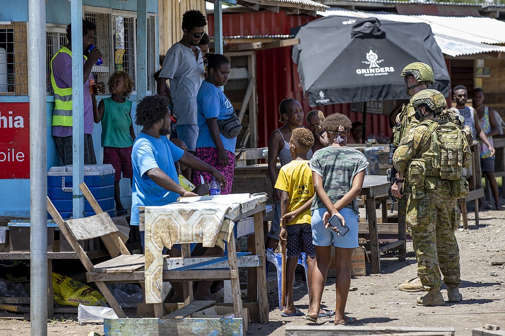 In this photo provided by the Department of Defence, Australian Army soldiers talk with local citizens during a community engagement patrol through Honiara, Solomon Islands, Saturday, Nov. 27, 2021. Solomon Islands police have found multiple bodies in a burned-out building and arrested more than 100 people in this week&#x27;s violence sparked by concerns about the Pacific nation&#x27;s increasing links with China. (Cpl. Brandon Grey/Department of Defence via AP)