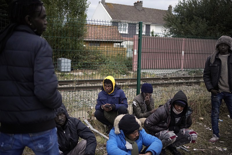 FILE- Migrants wait for food distribution at a camp in Calais, northern France, Thursday, Oct. 14, 2021. The price to cross the English Channel varies according to the network of smugglers, between 3,000 and 7,000 euros. Often, the fee also includes a very short-term tent rental in the windy dunes of northern France and food cooked over fires that sputter in the rain that falls for more than half the month of November in the Calais region. (AP Photo/Christophe Ena, File)