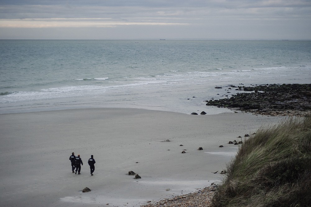 FILE- French police officers patrol on the beach in the searcher migrants in Wimereux, northern France, Wednesday, Nov.17, 2021. The price to cross the English Channel varies according to the network of smugglers, between 3,000 and 7,000 euros. Often, the fee also includes a very short-term tent rental in the windy dunes of northern France and food cooked over fires that sputter in the rain that falls for more than half the month of November in the Calais region. (AP Photo/Louis Witter, File)