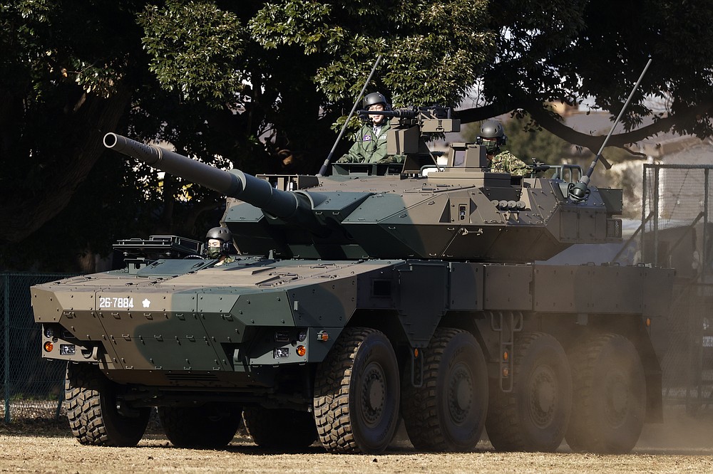 Japan's Prime Minister Fumio Kishida, left, rides on a Japan Ground Self-Defense Force (JGSDF) Type 16 maneuver combat vehicle during a review at the JGSDF Camp Asaka in Tokyo, Japan, Saturday, Nov. 27, 2021. (Kiyoshi Ota/Pool Photo via AP)