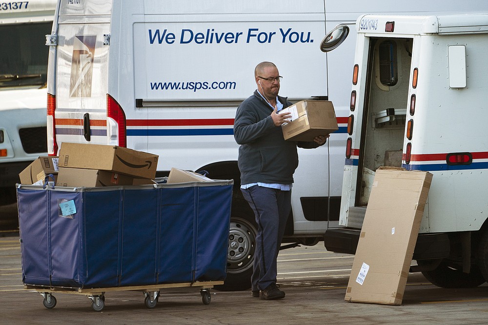 A postal carrier loads boxes into his delivery vehicle, Monday, Nov. 8, 2021, in Portland, Maine. With memories of last year&#x27;s pandemic-related holiday crush, postal workers in distribution hubs are gearing up for another busy season. (AP Photo/Robert F. Bukaty)