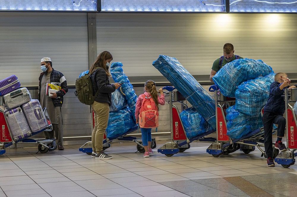 FILE - People line up to get on an overseas flight at OR Tambo International Airport in Johannesburg, South Africa, Nov. 26, 2021. As the world grapples with the emergence of the new highly transmissible variant of COVID-19, worried scientists in South Africa — where omicron was first identified — are scrambling to combat its lightning spread across the country. (AP Photo/Jerome Delay, File)