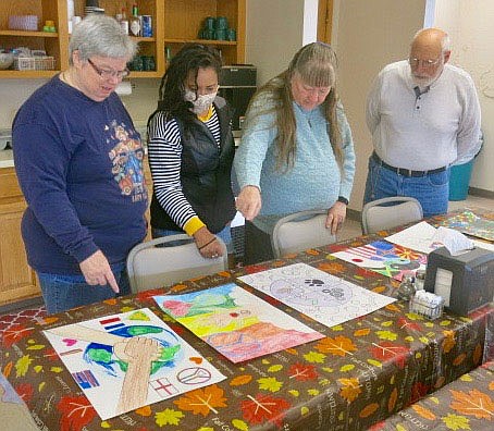 Westside Eagle Observer/SUSAN HOLLAND
Members of the Gravette Lions Club look over posters in the local Lions Club International Peace Poster Contest. Judging was done Tuesday, Nov. 9, and the winning poster was sent on to district competition. Pictured discussing entries in the annual contest are Lion members Sue Rice, Cela Gaytan, Linda Damron and Jeff Davis.