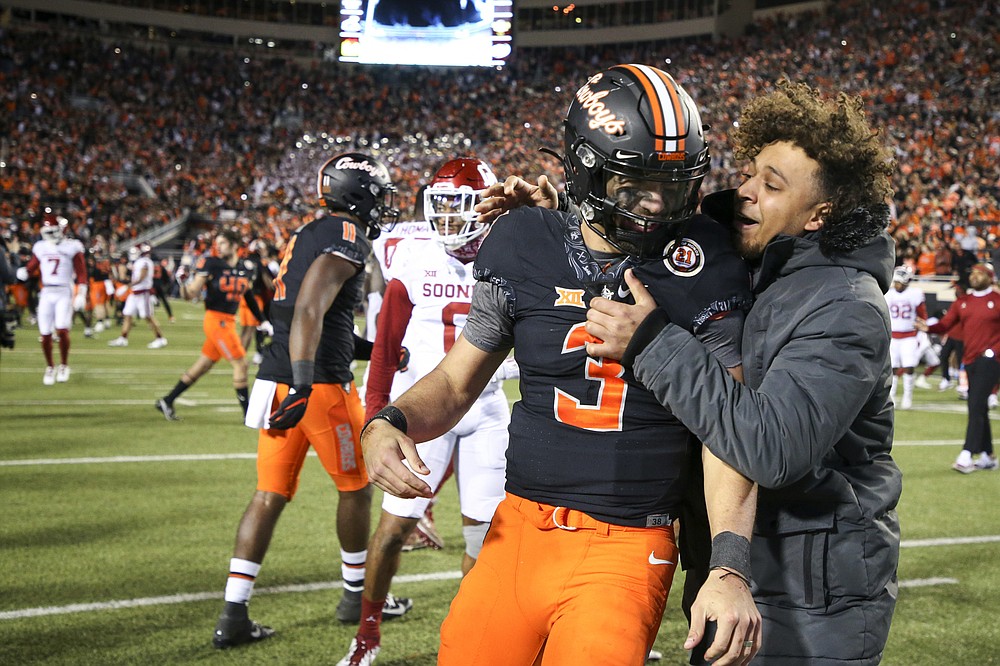 A fan celebrates with Oklahoma State quarterback Spencer Sanders (3) after Oklahoma State's 37-33 win over Oklahoma during an NCAA college football game in Stillwater, Okla., Saturday, Nov. 27, 2021. (Ian Maule/Tulsa World via AP)