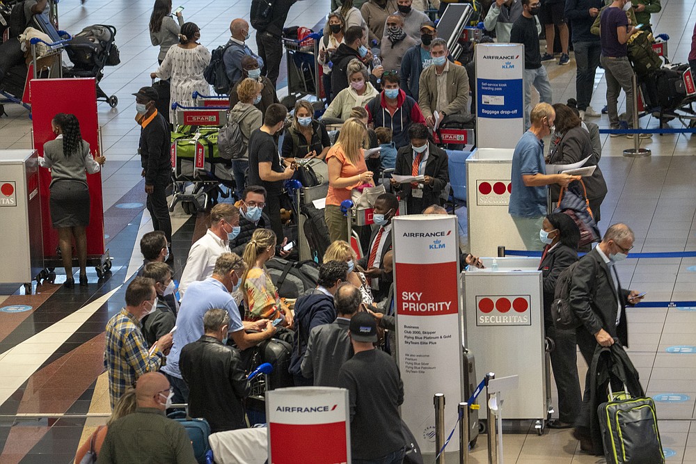 FILE - People queue to get on the Air France flight to Paris at OR Tambo's airport in Johannesburg, South Africa, Nov. 26, 2021. As the world grapples with the emergence of the new highly transmissible variant of COVID-19, worried scientists in South Africa — where omicron was first identified — are scrambling to combat its lightning spread across the country. (AP Photo/Jerome Delay, File)
