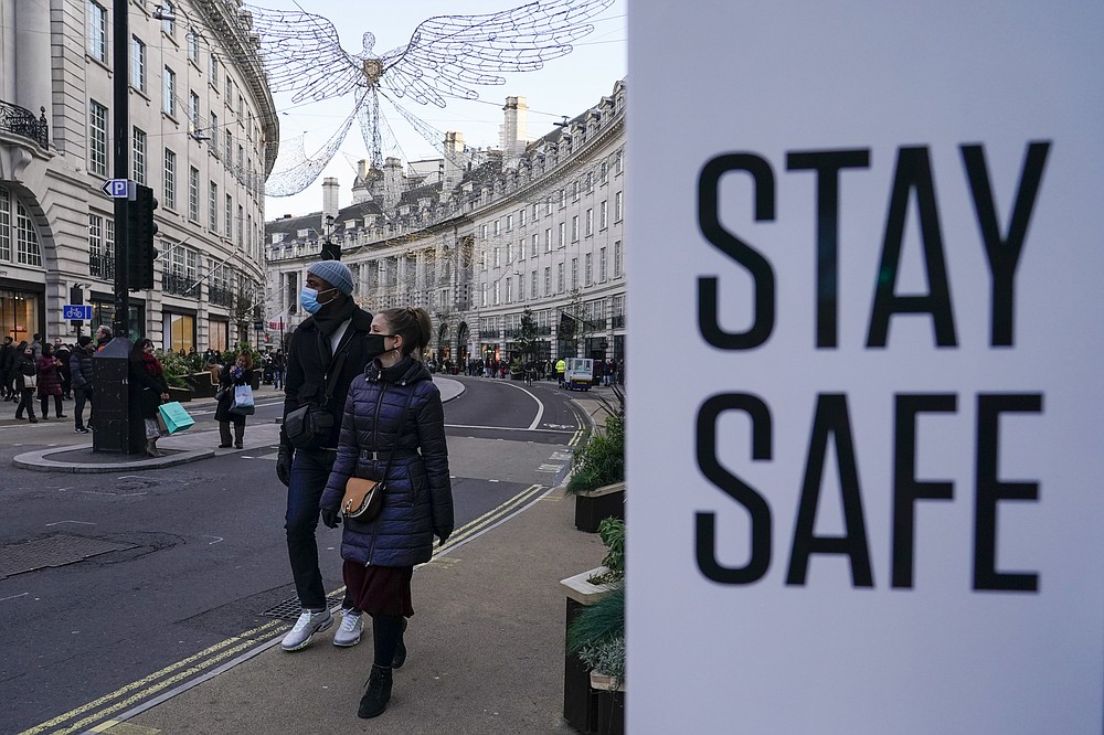 People wear face masks as they walk, in Regent Street, in London, Sunday, Nov. 28, 2021. Britain&#x27;s Prime Minister Boris Johnson said it was necessary to take &quot;targeted and precautionary measures&quot; after two people tested positive for the new variant in England. He also said mask-wearing in shops and on public transport will be required. (AP Photo/Alberto Pezzali)