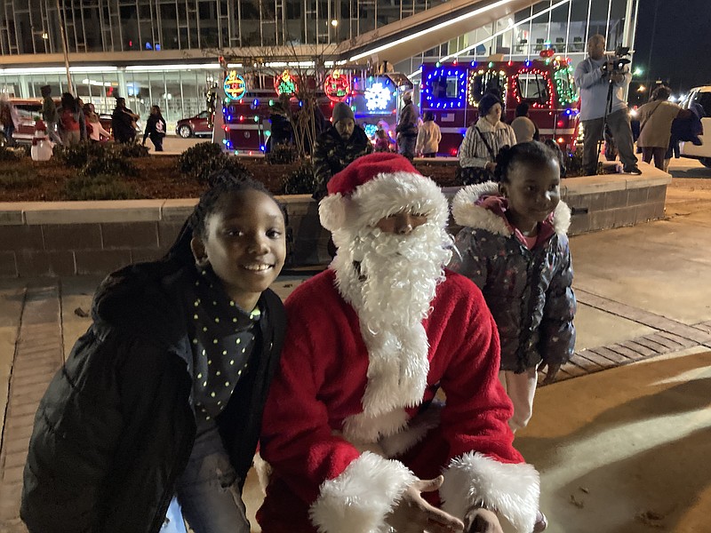 Tiona Edwards, 8, and her sister, Neveah, 4, pose with Santa at Sunday night's Christmas tree lighting event at the downtown plaza. (Pine Bluff Commercial/Byron Tate)
