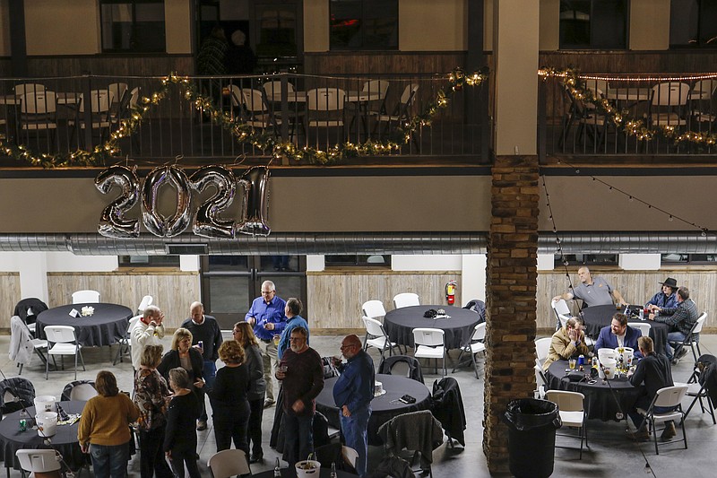 News Tribune file

People gather in idle conversation just before dinner is served at a New Year's Eve to close out 2020 at the Capital Bluffs Event Center.