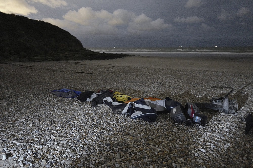 FILE- Life jackets, sleeping bags and damaged inflatable small boat are pictured on the shore in Wimereux, northern France, Friday, Nov. 26, 2021 in Calais, northern France. The price to cross the English Channel varies according to the network of smugglers, between 3,000 and 7,000 euros. Often, the fee also includes a very short-term tent rental in the windy dunes of northern France and food cooked over fires that sputter in the rain that falls for more than half the month of November in the Calais region. (AP Photo/Rafael Yaghobzadeh, File)