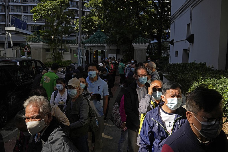 People wearing face masks, line up to receive China's Sinovac COVID-19 coronavirus vaccine at a community vaccination center in Hong Kong, Monday, Nov. 29, 2021. The emergence of the new omicron variant and the world&#x2019;s desperate and likely futile attempts to keep it at bay are reminders of what scientists have warned for months: The coronavirus will thrive as long as vast parts of the world lack vaccines.  (AP Photo/Kin Cheung)