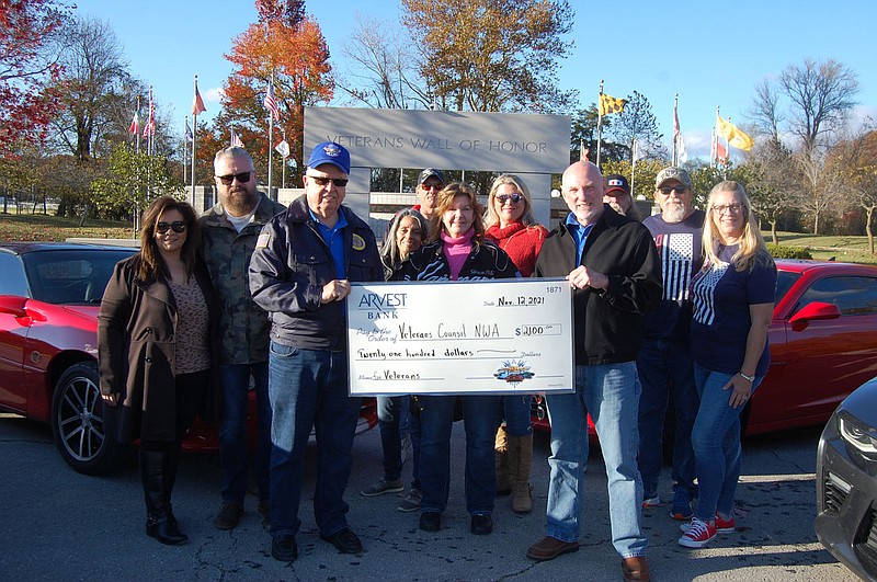 Bennett horne/The Weekly Vista Winona Brackeen (center), president of the Northwest Arkansas Camaro Club, and club members present a check in the amount of $2,100 to Veterans Council of Northwest Arkansas President Emeritus Ray Brust (left) and President Roger Armstrong on Nov. 12. The check is the first donation to the council's project of expanding the Veterans Wall of Honor.