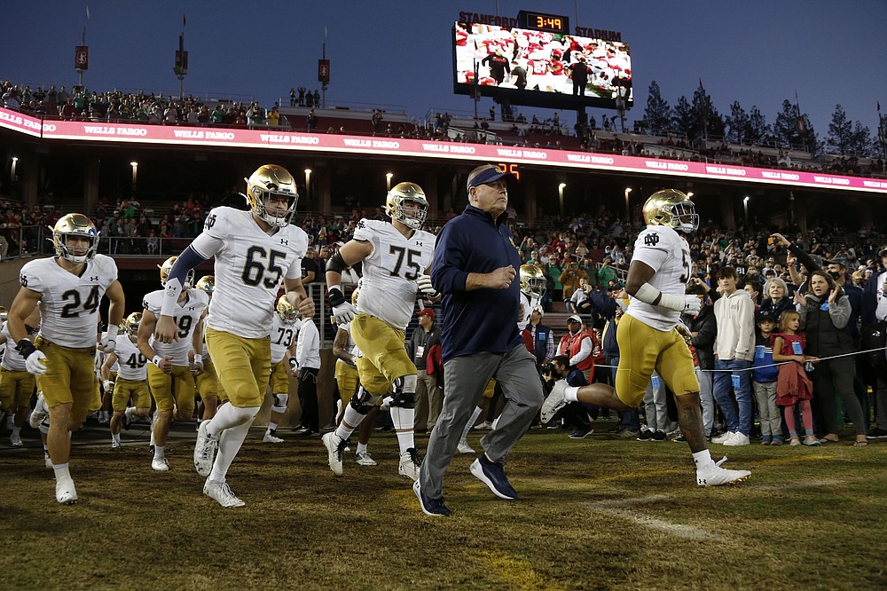 Notre Dame coach Brian Kelly, center, runs onto the field for the team&#x27;s NCAA college football game against Stanford in Stanford, Calif., Saturday, Nov. 27, 2021. (AP Photo/Jed Jacobsohn)