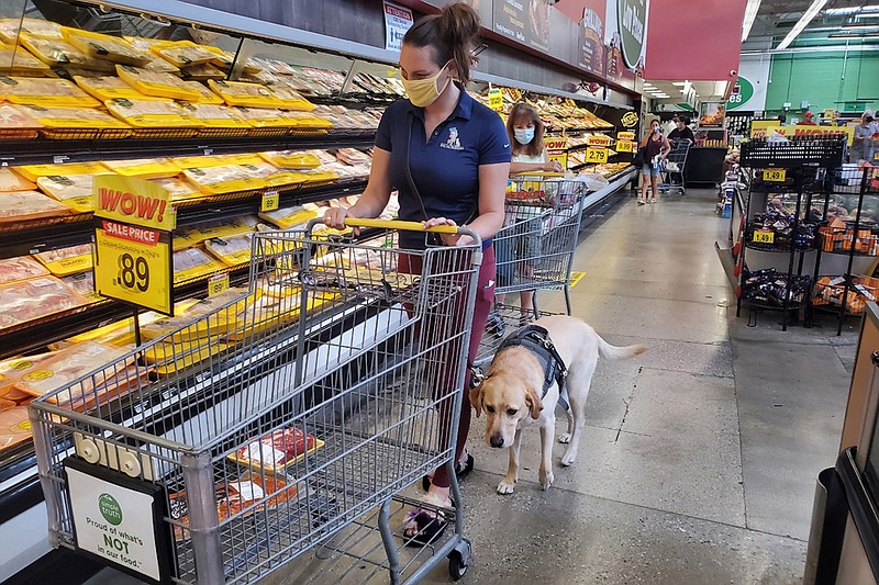 Danyelle Clark-Gutierrez and her service dog, Lisa, shop for food at a grocery store. Clark-Gutierrez got the yellow Labrador retriever to help her cope with post-traumatic stress disorder after she experienced military sexual trauma while serving in the Air Force. (Stephanie O'Neill/Kaiser Health News/TNS)